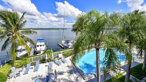 A pool area with lounge chairs and palm trees, overlooking a marina with boats. - Beautiful bayfront view! December 2026 dates available now! (Longboat Key)