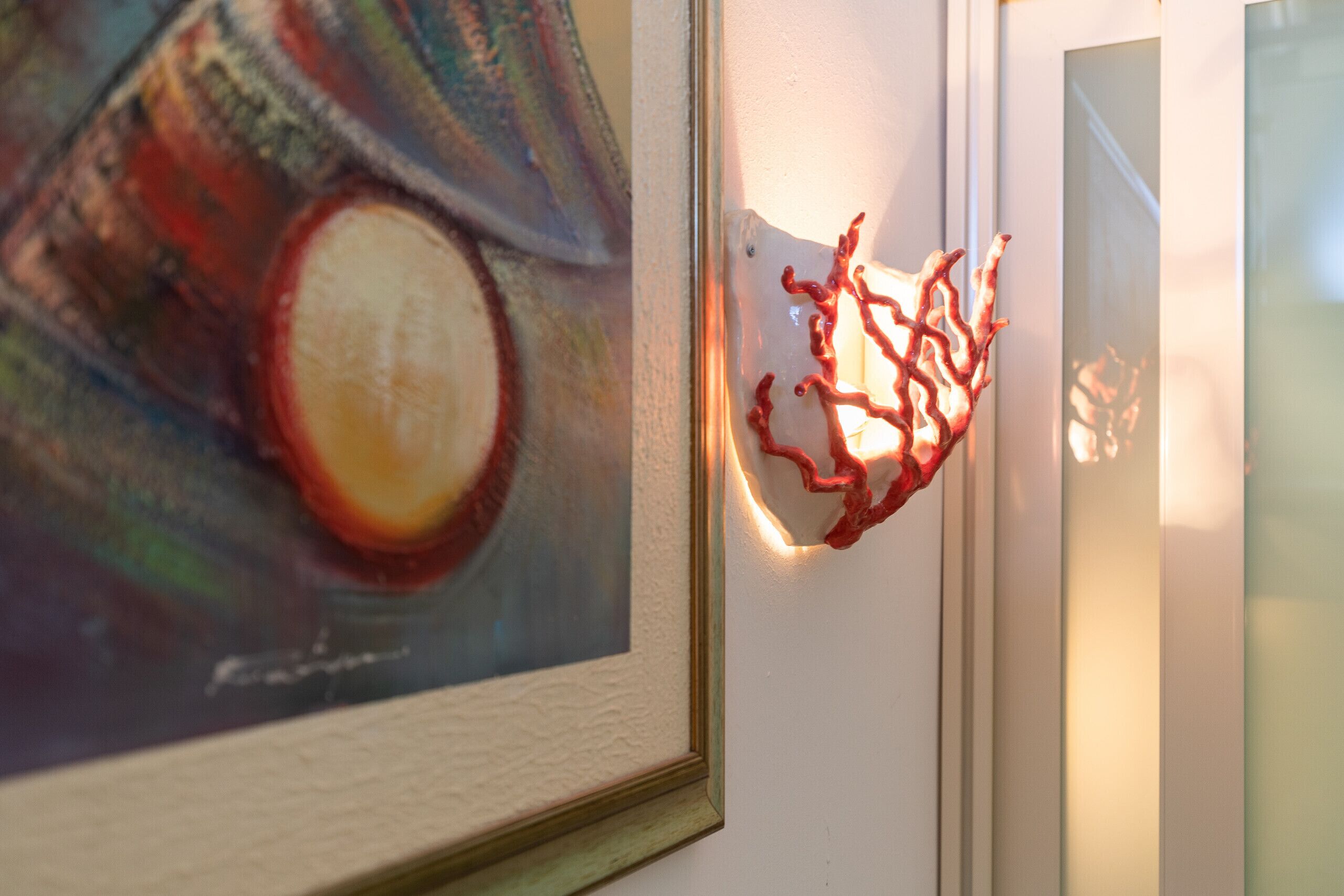 A framed abstract painting and a red abstract sculpture on a wall.