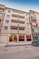 Un hotel de varios pisos con balcones, un restaurante a la vista y un estacionamiento.