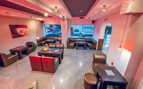 A modern lounge area with leather seating, a large window view of the street, and a contemporary art piece on the wall.