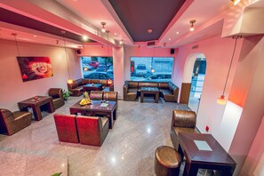 A modern lounge area with leather seating, a large window view of the street, and a contemporary art piece on the wall. - Family Hotel Gran Ivan (Varna)