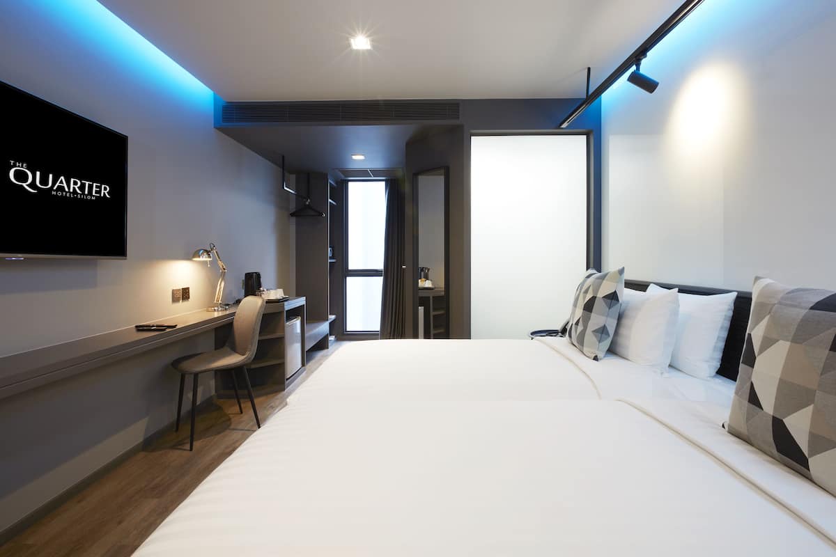 A modern hotel room with a large bed, a desk, and a TV mounted on the wall.