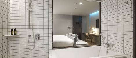 A modern bathroom with a large mirror, a bathtub, and a shower.