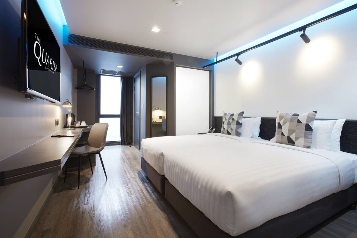 A modern hotel room with a large bed, a desk, and a TV mounted on the wall.