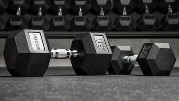 A set of hexagonal dumbbells with weight markings, arranged on a floor.