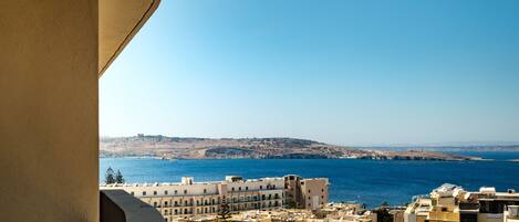 A coastal cityscape with buildings and a clear blue sea.