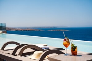 A poolside table with two drinks and a straw, overlooking a clear blue sea. - Mayflower Hotel (St. Paul's Bay)