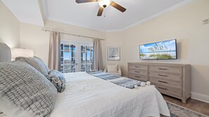 Quarto com cama, cômoda, televisão e janela com cortinas.