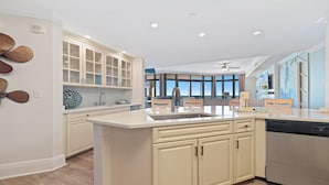 Een moderne keuken met een centraal eiland, inbouwmeubels en uitzicht op de woonkamer.