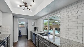 A modern kitchen with granite countertops, white subway tiles, and a built-in dishwasher.