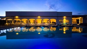 A modern hotel with a swimming pool, multiple balconies, and warm lighting. - Storms Resort (Nanyuki)