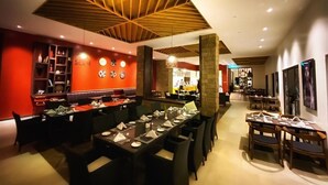 A modern restaurant with a central dining area, a bar, and a kitchen in the background. - Storms Resort (Nanyuki)
