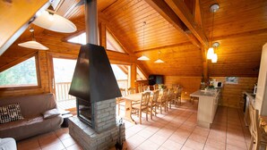A spacious wooden cabin with a stone fireplace, a dining area, and a kitchen. - Oz/Alpe d'Huez 110m slopes, up to 21 people, Hammam, en-suite bedrooms (Oz)
