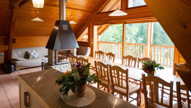A wooden cabin interior with a dining area, a fireplace, and large windows. - Oz/Alpe d'Huez 110m slopes, up to 21 people, Hammam, en-suite bedrooms (Oz)