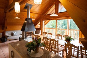 A wooden cabin interior with a dining area, a fireplace, and large windows. - Oz/Alpe d'Huez, 110 m of slopes, accommodates up to 21 people, hammam, bedroom with private bathroom (Oz)