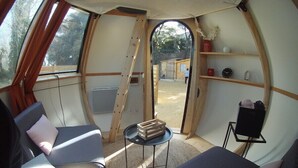 A cozy interior of a dome-shaped tent with two beds, a small table, and a shelf with personal items. - Nuit Etoilé (Mondragon)