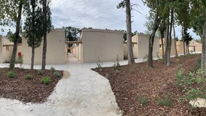 A pathway leading to a row of beige buildings with a clear sky above.