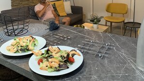 A modern living room with a sofa, a dining table with plates of food, and two pendant lights.