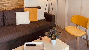 A modern living room with a dark brown sofa, a yellow chair, a white coffee table, a floor lamp, and a hanging pendant light.