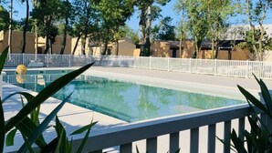 A swimming pool surrounded by a white fence, with trees and buildings in the background.