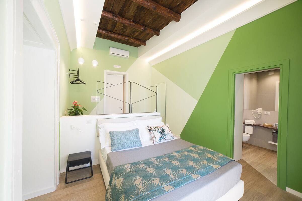 A bedroom with a bed, bedside table, and a view into the bathroom.