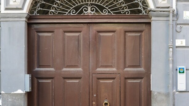 Unas grandes puertas dobles marrones con una rejilla metálica decorativa en la parte superior.
