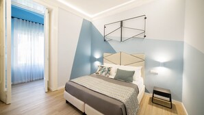 Un dormitorio moderno con cama, mesita de noche y decoración mural geométrica.