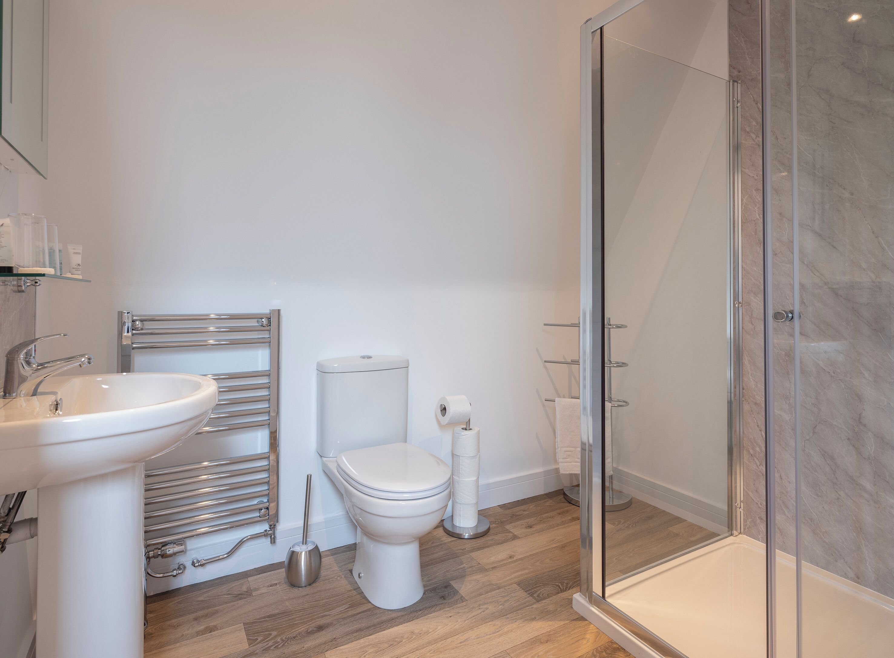 Un baño moderno con lavamanos, inodoro y cabina de ducha de vidrio.