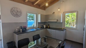 Una cocina moderna con comedor, ventanas amplias y un reloj en la pared.