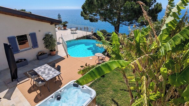 Zona de piscina con jacuzzi, mobiliario exterior y vistas al mar.