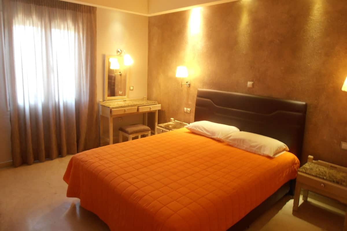 A hotel room with a bed, a nightstand, a dresser, a mirror, and two wall-mounted lamps.
