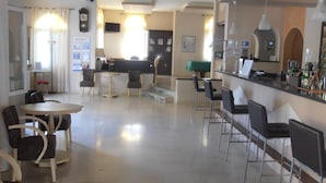 A modern hotel lobby with a reception desk, bar area, and seating. - Frosini Gardens (Corfu)