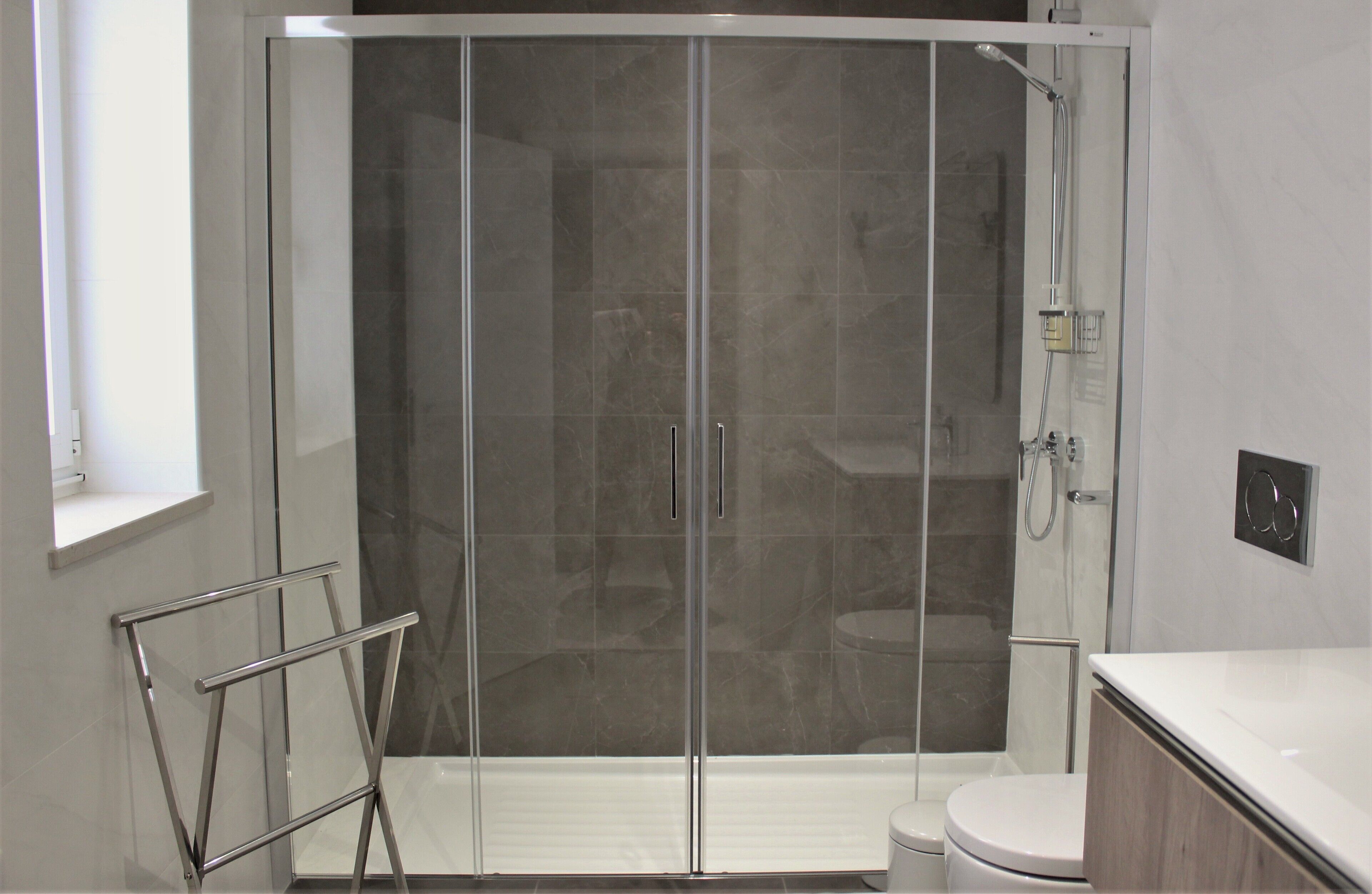A modern bathroom with a glass-enclosed shower, a toilet, and a vanity with a mirror.