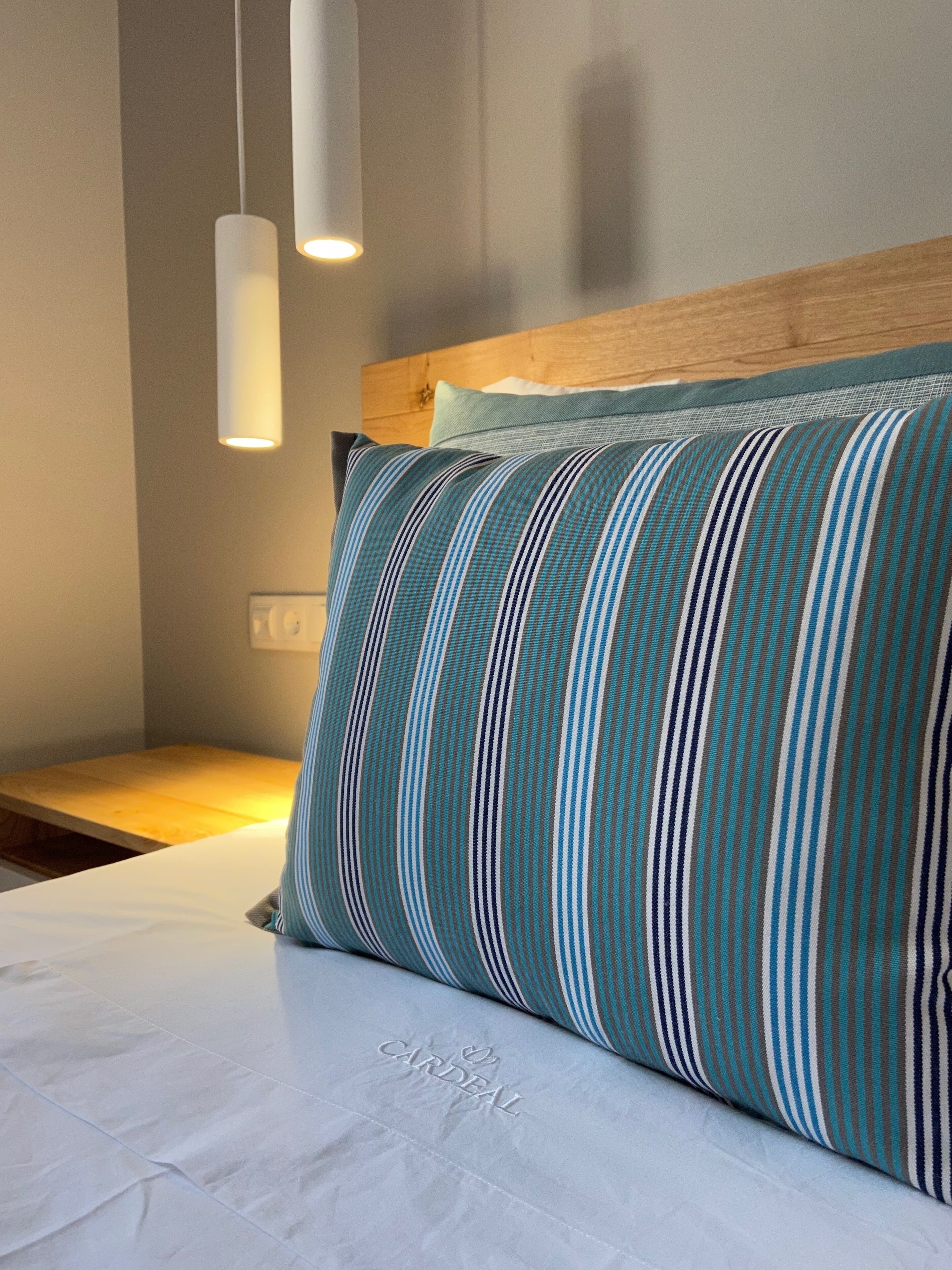 A neatly made bed with a striped pillow and a headboard.