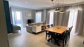 A modern living room with a sofa, TV, and dining area. - Cardeal Suites & Apartments (Faro)