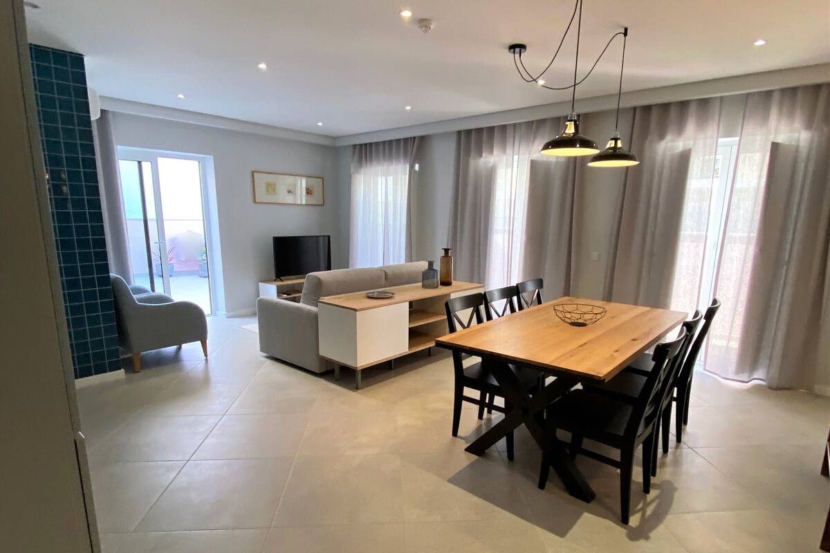 A modern living room with a sofa, TV, and dining area.