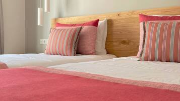 A hotel room with a wooden headboard, two beds with white bedding, and pink and striped pillows.