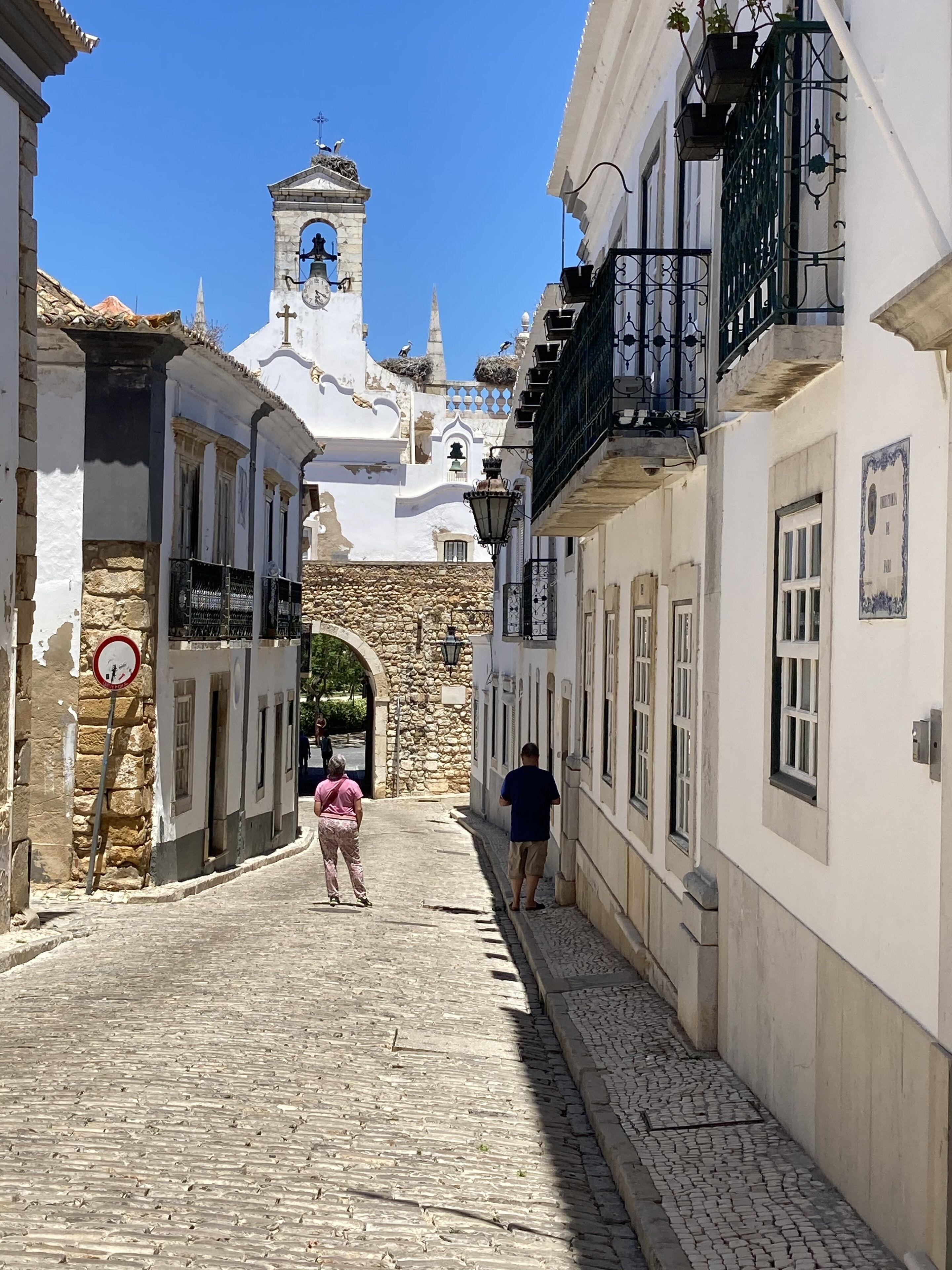 A cobblestone street leading to a historic building with a bell tower.