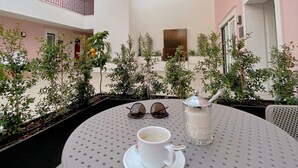 A round table with a cup and saucer, sunglasses, and a sugar bowl. - Cardeal Suites & Apartments (Faro)