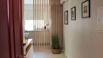 Un pasillo con un separador de madera, una planta en maceta y cuadros en la pared.