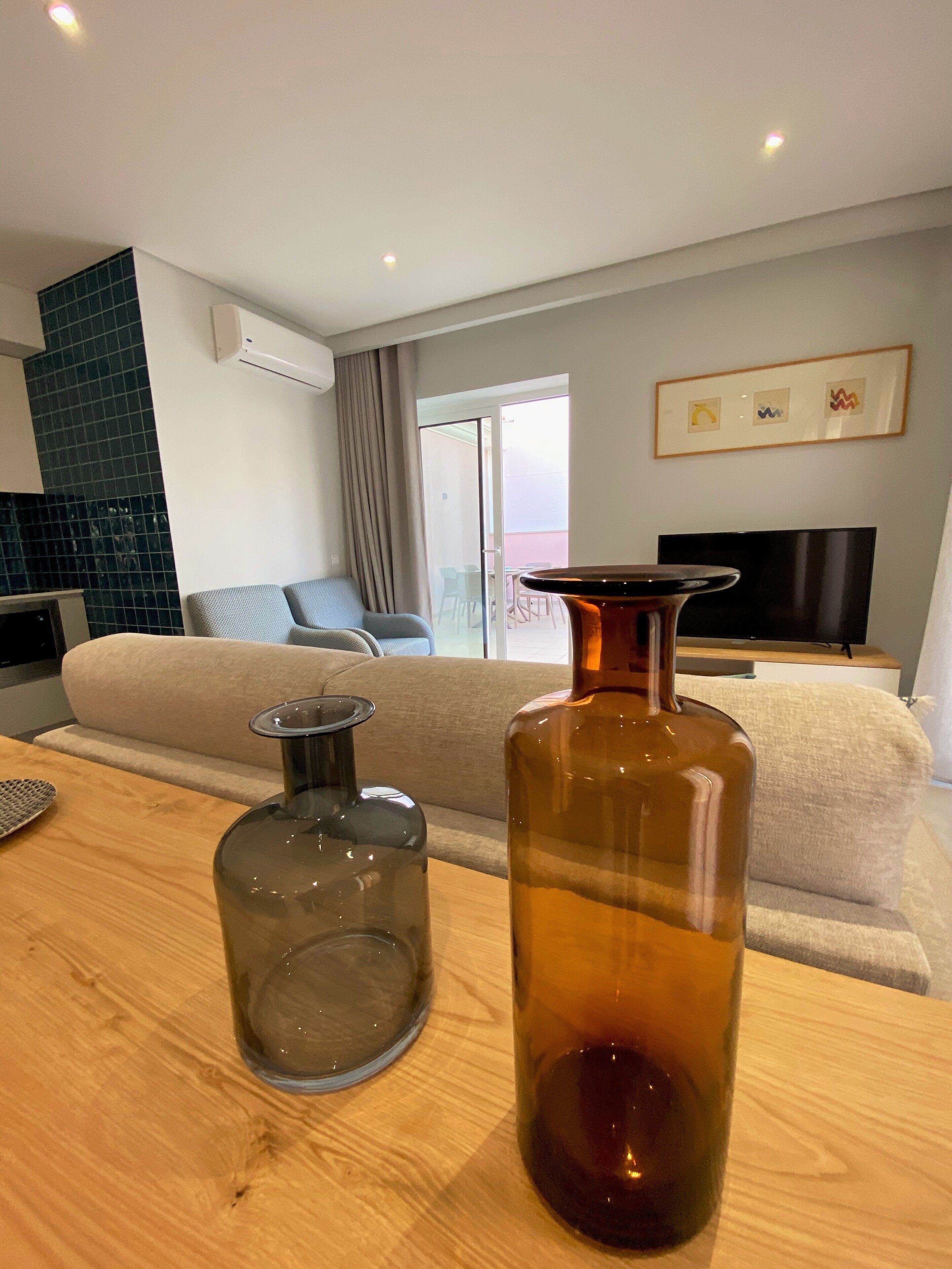 Un salon moderne avec un canapé, une table basse, un téléviseur et un balcon offrant une vue agréable.