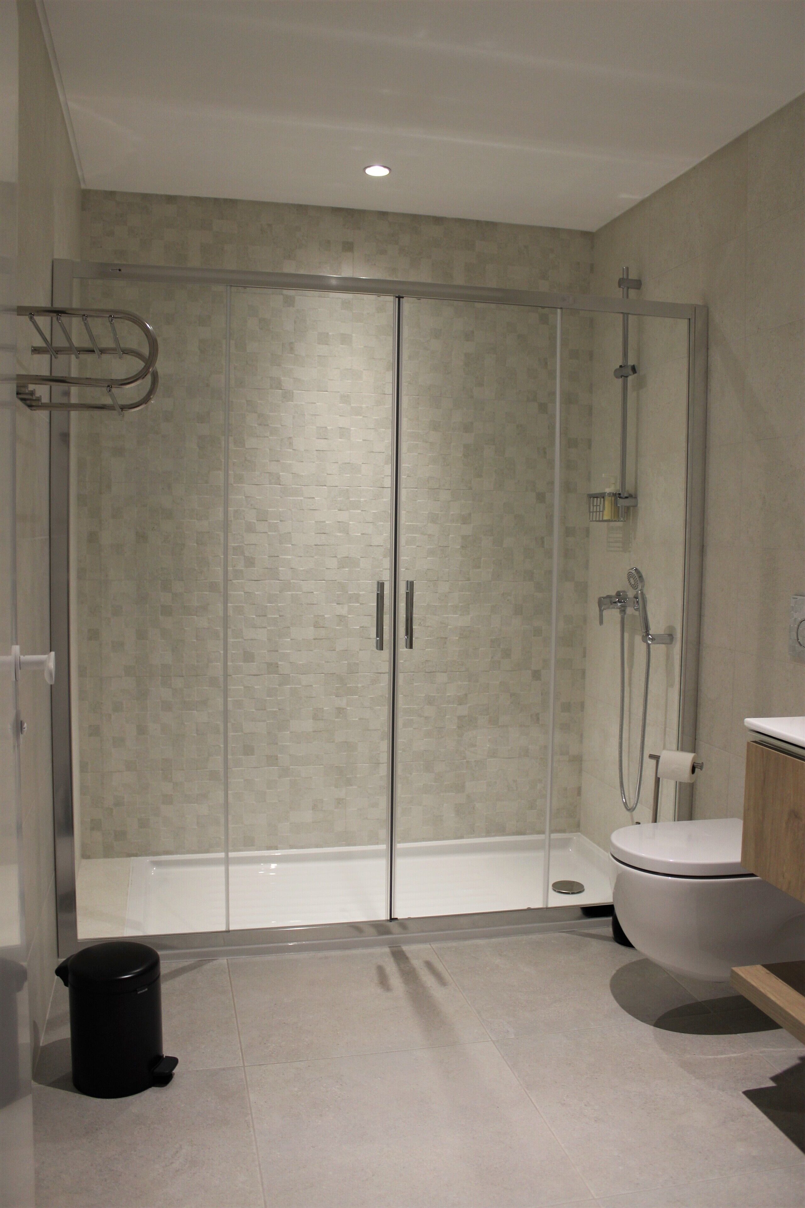 A modern bathroom with a glass-enclosed shower, a white toilet, and a sink.