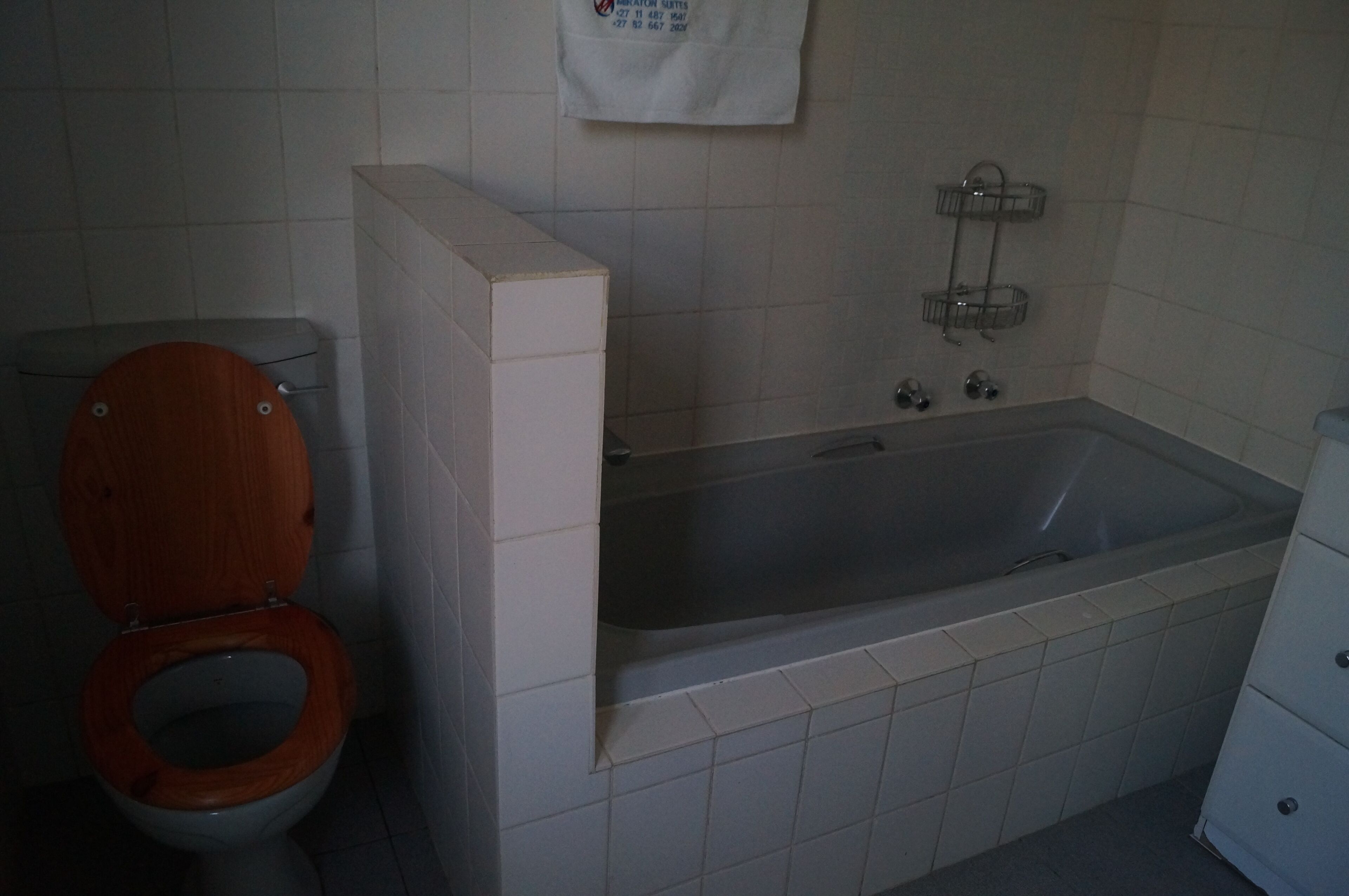 Een badkamer met een houten toilet, een badkuip en een douchegedeelte.