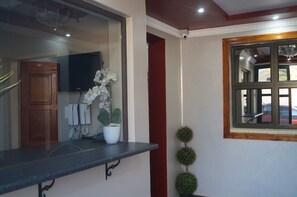A reception area with a counter, a potted orchid, a wall-mounted telephone, and a television on the wall.