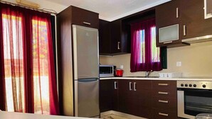 A compact kitchen with dark wooden cabinets, a stainless steel refrigerator, a microwave, and an oven. - Villas Nine Muses - Villa Efterpi 3 bdr villa (Hersonissos)