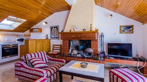 Una sala de estar acogedora con chimenea, techo de madera y televisor.