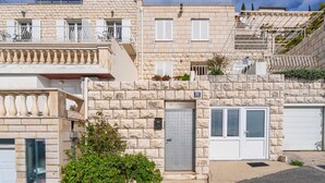 Un edificio residencial de varios pisos con fachadas de piedra, balcones y un portón de garaje.