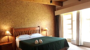 A bed with a wooden headboard, two bedside lamps, and a green bedspread. - Die Plasie (Pretoria)