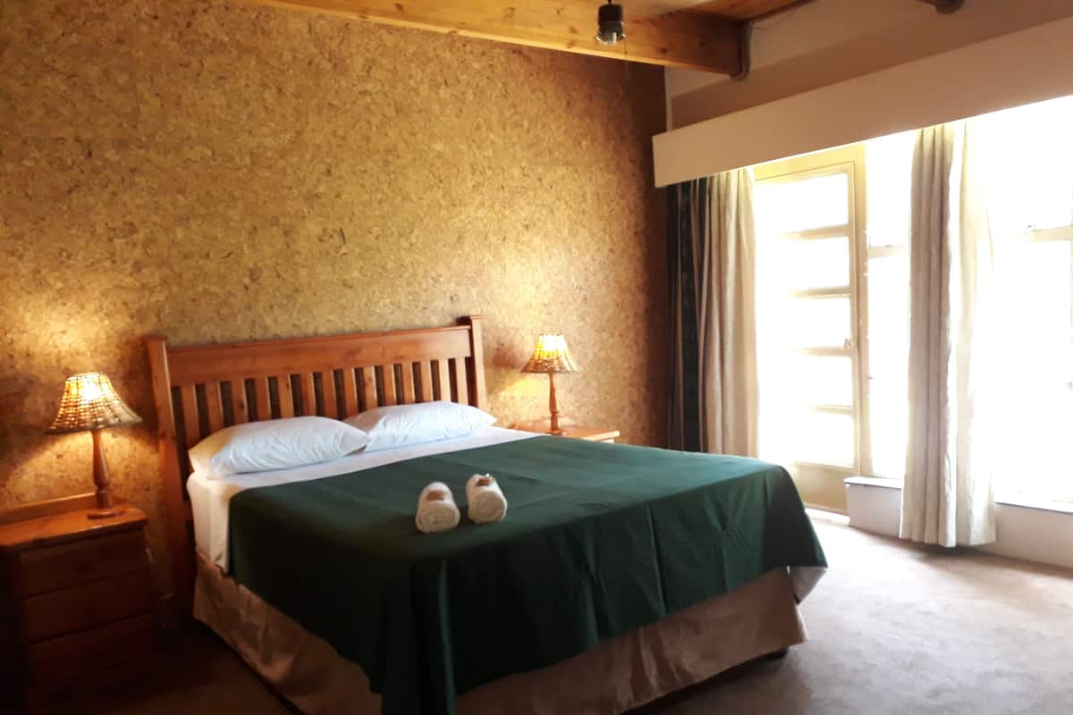 Un lit avec une tête de lit en bois, deux lampes de chevet et une couvre-lit verte.
