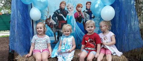 Um grupo de crianças sentadas em fardos de feno em frente a um cenário da Disney Frozen.